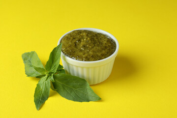 Bowl of Pesto sauce and basil on yellow background