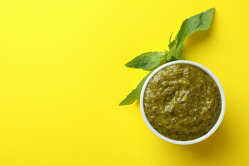 Bowl of Pesto sauce and basil on yellow background