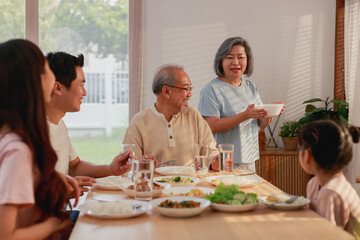 Asian extended family having breakfast together at home. Asian Big family grandparents parents and...