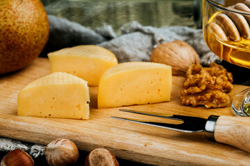 Cheese dish with organic cheeses, fruits, nuts on a wooden background. Delicious cheese snack