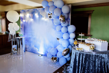 Blue photo zone with balloons, banner and macarons on birthday party