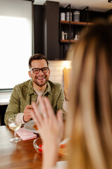Happy young couple eating and drinking wine at home. Focus on man.