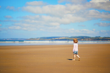 Fototapeta na wymiar Adorable toddler girl on the sand beach at Atlantic coast