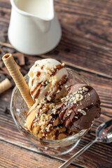 Chocolate, cream and caramel Roma ice cream in a glass bowl with hazelnut and chocolate sauce poured over it.