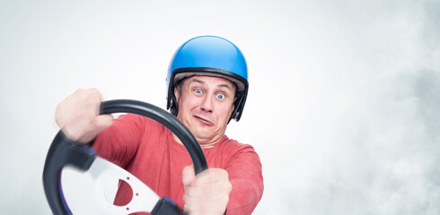 Emotional man in a blue motorcycle helmet enters a turn holding a steering wheel in his hands,...