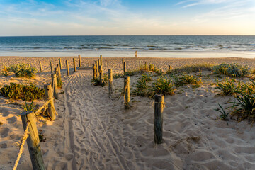 Wide sandy Faro beach with dunes and walkways by the sunset, Algarve, Portugal