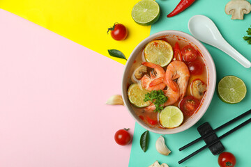 Concept of tasty eating with Tom yum soup on multicolor background