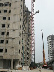 A building under construction with a passenger hoist and a mobile crane