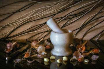 Garlic and a white stone mortar with pestle. Ingredients for cooking and alternative medicine....