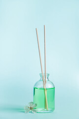 Aromatic diffuser and flowers on a blue background. Spa and relaxation concept. Fragrances for home.