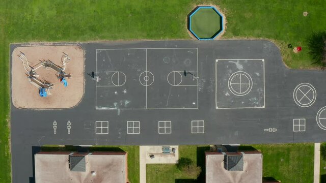 School playground for recess. Top down aerial drone shot of four square, basketball court. No students. Outdoor recess.