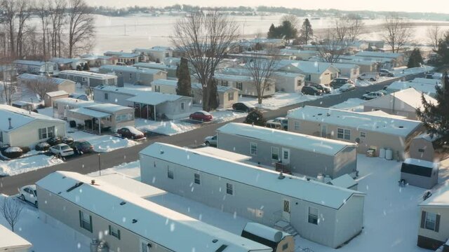 Winter snow falls on rural mobile home park in poor Appalachian community. Residential trailers during cold blizzard.
