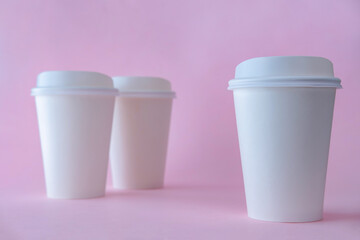 Three white paper coffee cups on pink background, coffee cup mock up.