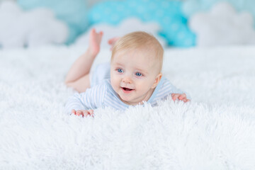 smiling baby boy on the bed goes to bed or wakes up in the morning