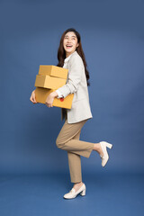 Happy Asian businesswoman holding package parcel box isolated on blue background, Delivery courier...