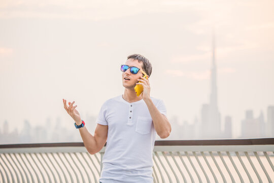 Chatty Man Is On The Phone For Work Or For Fun And Gestures Against The Backdrop Of Dubai Creek And The Burj Khalifa