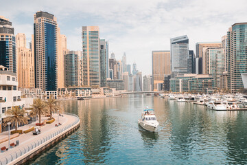 Fototapeta na wymiar The boat sails along the canal in the Dubai Marina area against the backdrop of numerous residential skyscrapers and hotels