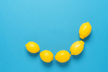 Semicircle of fresh lemons on a blue paper background. Top view, flat lay.