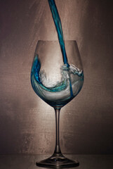 pouring blue liquid in wine glass
