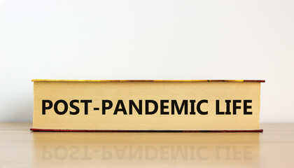 Covid-19 post-pandemic life symbol. Concept words 'post-pandemic life' on book on wooden table. Beautiful white background. Covid-19 post-pandemic life and medical concept.