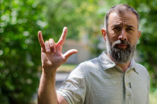 Cropped image of a man in casual clothes show hand sign "I love you". Body language. Hand is showing a sign "I love you"