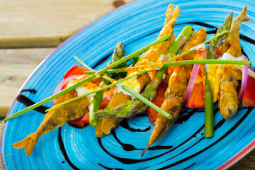 Delicious pan-fried battered sprats with creamy ginger sauce, greens, tomatoes seasoned with...