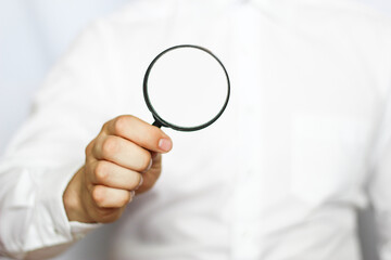 A businessman in a white shirt is holding a magnifying glass. white background. business and finance