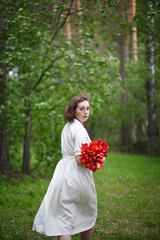 beautiful young girl walks in the garden with a bouquet of tulips, brunette in a body dress. Bouquet of tulips. Spring time.