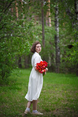 beautiful young girl walks in the garden with a bouquet of tulips, brunette in a body dress. Bouquet of tulips. Spring time.