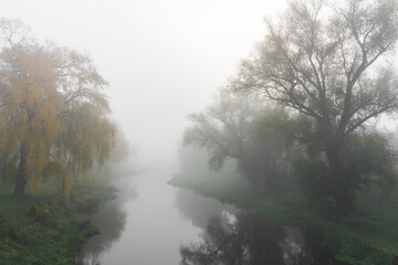 Autumn landscape with thick fog on the river