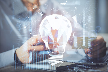 Double exposure of man's hands holding and using a digital device and bulb hologram drawing. Idea concept.