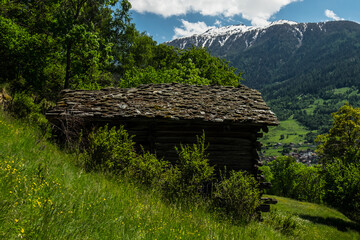 Fototapeta na wymiar Small wood and stone shelter, with snowy mountains in the background, shot in the 