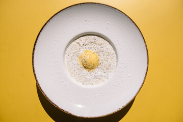 Oatmeal porridge with bowl of passion fruit ice cream and coconut flakes. Yellow background of summer terrace