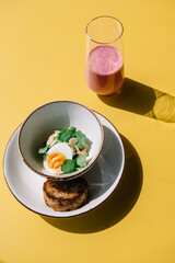 cold beet soup with kefir, fresh herbs, boiled egg and slice of grilled bread on the table of cafe summer terrace