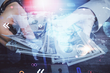 Double exposure of world map drawing hologram and us dollars bills and man hands.