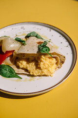 Omelette in lavash with slices of pepper and spinach leafs on a plate