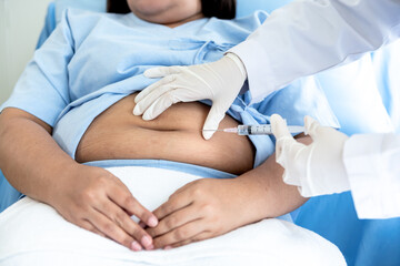 Doctor was about to inject insulin vaccine on abdomen, fat woman patient which admitted to treatment from diabetes and obesity,  to people health care and diabetes concept.