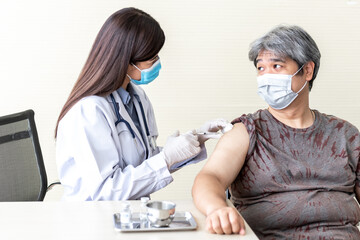 Asian attractive woman doctor, wearing a surgical mask, is administering a vaccination COVID-19, treatment to elderly fat man with diabetes, to health care and vaccine for people concept.