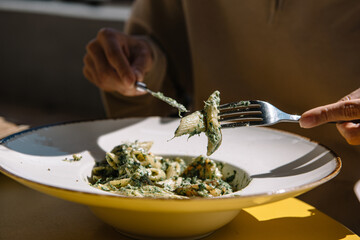 person eating Italian pasta with pine nuts and a lot of parmesan cheese.