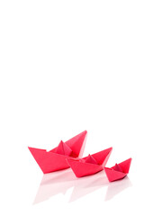 Red paper origami boats over white background.