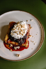 dessert with brioche bread, cream, currant jam and nuts on a plate