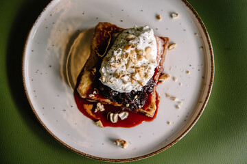 dessert with brioche bread, cream, currant jam and nuts on a plate