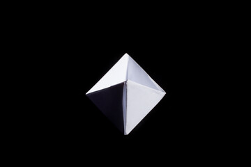 Top view of a white origami paper boat on black background.