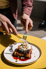 person eating dessert with brioche bread, cream, currant jam and nuts