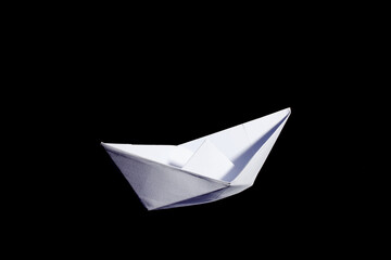 Top view of a white origami paper boat on black background.