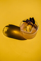 glass of basil smash cocktail on yellow table