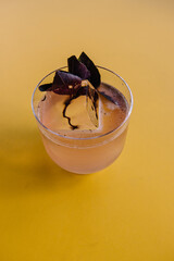 glass of basil smash cocktail on yellow table