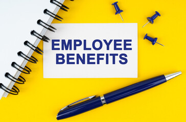 On a yellow background lies a notebook, a pen and a business card with the inscription - Employee benefits