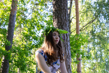 Beautiful blue eye girl in floral crown and dress in the sunnt sumer forest on river side