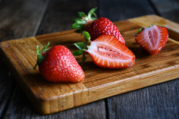 Strawberries cut in half on an old wooden table. Cooking in the kitchen.
